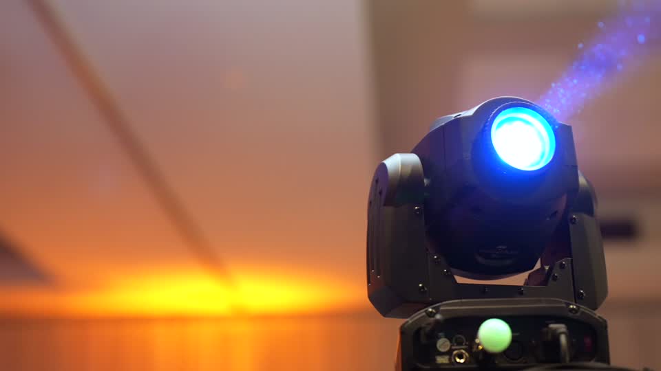 A moving head light beaming over a reception room with warm uplighting